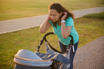 Obraz premium Young woman on maternity leave taking her baby out in a stroller. Mother with baby pram outdoors