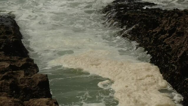 Disgusting solid and yellowish foam in ocean due to sea warming, global warming, tilt up and down following the wave.