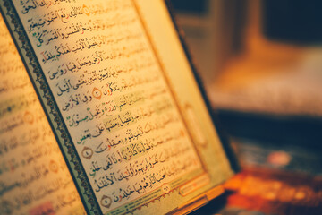 The pages of the Holy Quran are illuminated by a warm light.