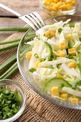 Tasty salad with Chinese cabbage, corn and cucumber in bowl on table, closeup