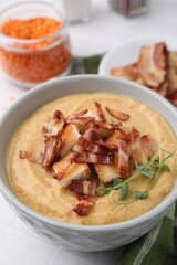 Delicious lentil soup with bacon and croutons on white table