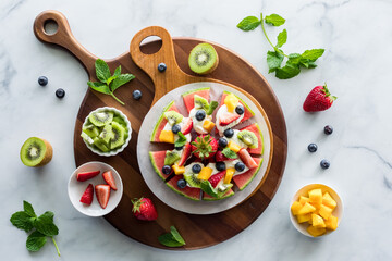 Top down view of a juicy watermelon pizza topped with fresh fruit pieces.