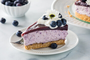 A slice of fresh blueberry cheesecake topped with whip cream and blueberries.