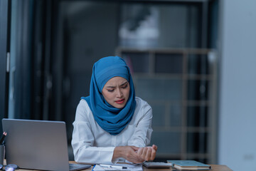 Cheerful muslim lady wear hijab working in the office, using laptop, Side view of smiling arab woman, freelancer typing on laptop, Muslim working woman concept.