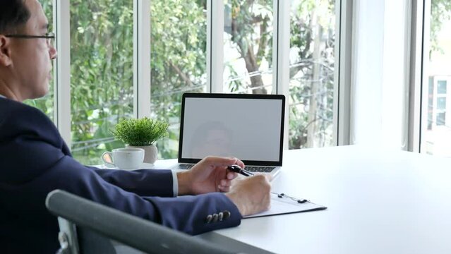 Closeup businessman hands working use laptop finance business document reading report paperwork spreadsheet at office desk. Man hands type keyboard write on office note check financial graph chart