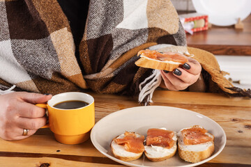 Woman having breakfast with coffee and toast with smoked salmon and cream cheese