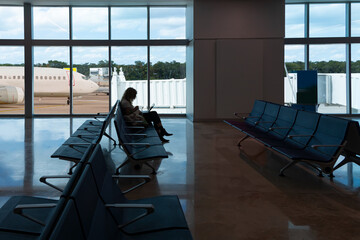 Silhouette of young woman working on laptop and waiting for flight in the Airport 