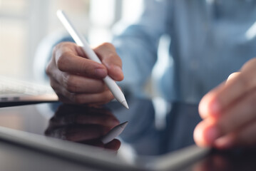 Business woman using stylus pen signing e-document on digital tablet via mobile app at office,...