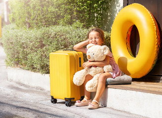 A child with a toy suitcase and a swimming circle waiting for a trip