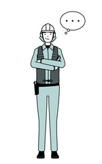 Senior female engineer in helmet and work wear with crossed arms, deep in thought.