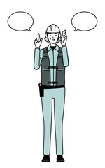 Senior female engineer in helmet and work wear pointing while on the phone.