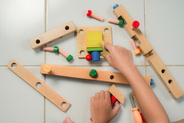 children hands playing with colorful wooden constructor puzzle bricks
