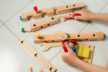 children hands playing with colorful wooden constructor puzzle bricks