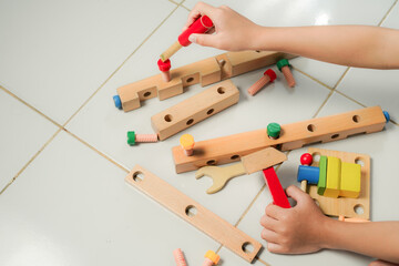 children hands playing with colorful wooden constructor puzzle bricks