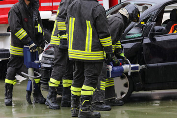 firefighter using powerful cordless pneumatic shears to open the jammed door of a crashed car after...