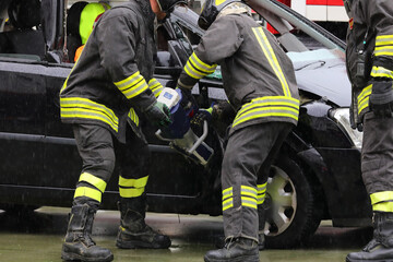 firefighter using cordless pneumatic shears to open the jammed door of a crashed car after a car accident