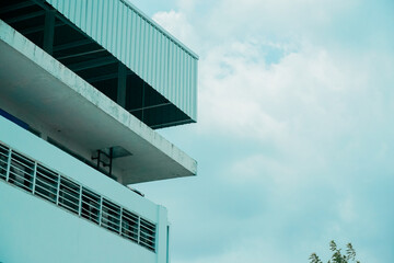 A tall building with a balcony and a cloudy sky in the background