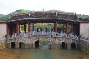 A bridge with a stone archway and a stone bridge over a river