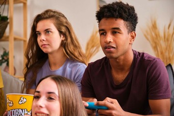 Young black man playing video games with his friends at shared student flat.