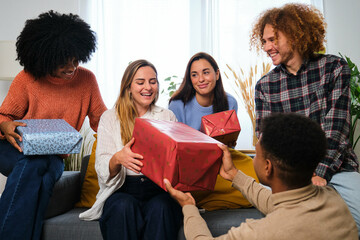 Young Caucasian woman receiving gifts in her birthday party celebration with multiracial friends.