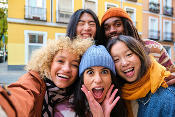 Multiracial group of friends taking selfie picture outdoors. Millennial people having fun on city street. International students smiling together at camera. Youth culture and community concept.