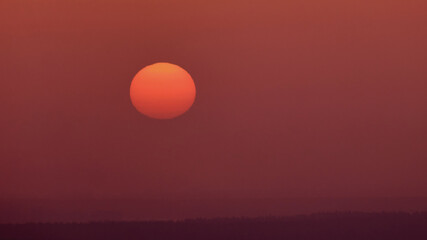 Fototapeta premium The sun sets in the mysterious haze of the evening red sky
