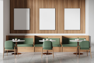 Modern cafe with green chairs, wooden wall panels, three empty frames, and white tables, light background. Cozy dining concept.  3D Rendering