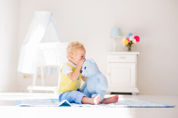 Little boy playing with toy teddy bear. Kids play.
