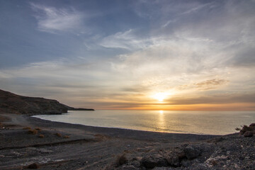 Sunrise with sea view in a secluded bay. rocky coast in warm colors. Landscape with a lava stone beach at Tarajalejo on Fuerteventura, Canary Islands, Spain.