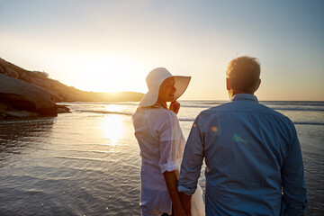Mature, happy couple and walking with love on beach in sunset for support or bonding in nature. Back view of man, woman or lovers enjoying romance, outdoor holiday or summer by water or ocean coast