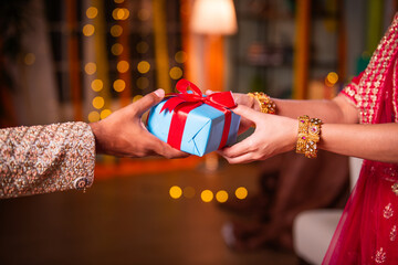 Indian asian woman wears gold bangles on festival day receiving gift box. closeup picture