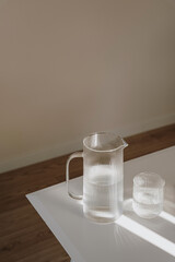 Decanter and glass of pure still water with sunlight shadow reflections