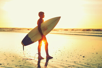 Sunset, beach and kid surf with board for adventure on vacation, holiday or silhouette water....