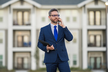 Real estate agent business man in suit hold holder clipboards and talking on phone. Businessman....