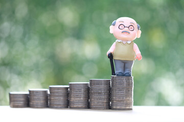 Retirement planning, Seniorman standing on stack of coins money on natural green background, Save money for prepare in future and pension retirement