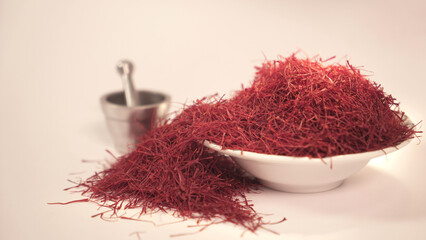 Saffron threads in a white porcelain dish next to the mortar