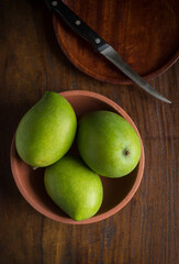 Fresh, big raw mangoes placed in a an earthen bowl, view from top. Popular Indian mangoes also called ‘King of fruit’.