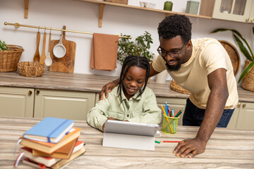 African American father and daughter doing homework together using tablet
