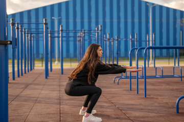 Woman in athletic wear Performing Squats on Outdoor Workout Equipment