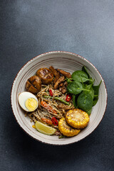 Asian cuisine. Noodles with egg and corn in a plate. On a dark background