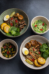 Asian cuisine. Noodles with egg and corn in a plate. On a dark background