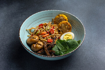 Asian cuisine. Noodles with egg and corn in a plate. On a dark background