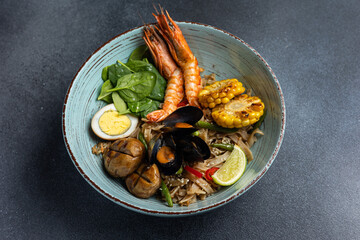 Asian cuisine. Noodles with egg and corn in a plate. On a dark background