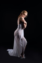 Fototapeta premium Sensual woman in white fabric in black studio
