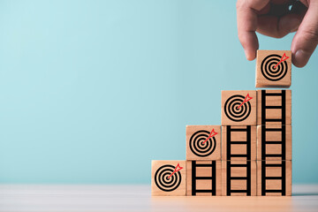 Hand put dartboard with arrow on the top of ladder for enhance and achievement setup business objective target goal concept.