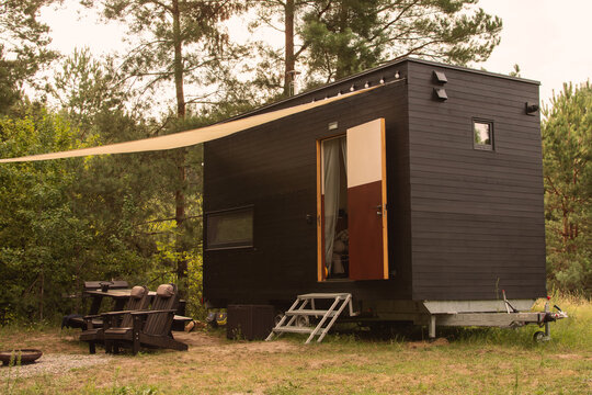 A modular frame-type apartment on wheels, lined with wood against the background of an autumn forest.