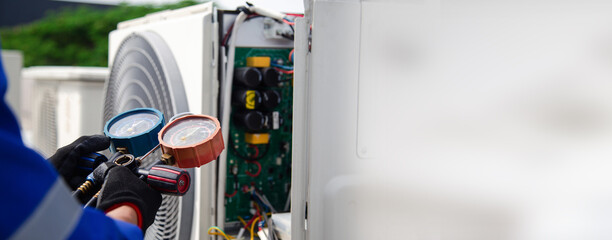 Air conditioner service .The air conditioner technician is using a gauge to measure the refrigerant...