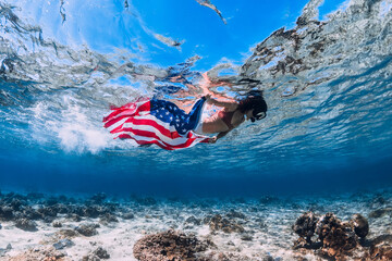 Woman swim underwater in blue ocean with US flag. Independence day concept.