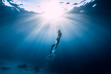 Freediver girli with diving fins and amazing sun rays.