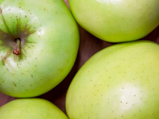 A cluster of ripe green apples, their glossy skins dotted with natural imperfections.